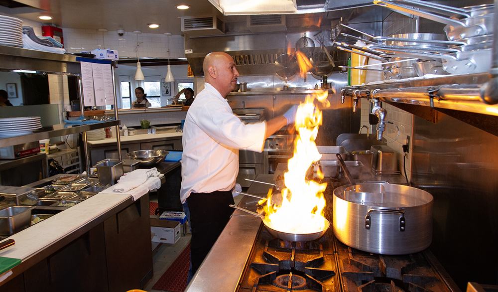 Chef flambéing a pan in the open kitchen